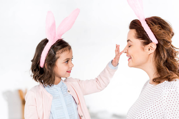 Happy mother and daughter in bunny ears playing on white  - Photo, image
