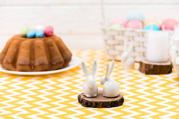 Ceramiczne zające stojący na stole z chleb Wielkanoc i pisanki - Zdjęcie, obraz