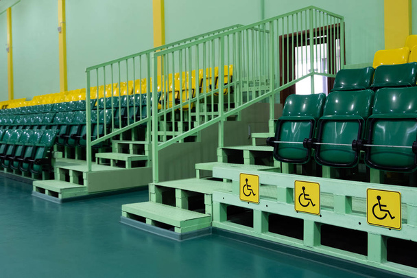 Zöld és sárga ülőhely és a fogyatékkal élők számára. Ülő ülések sportcsarnok. Szabad hely. Nem az emberek. - Fotó, kép