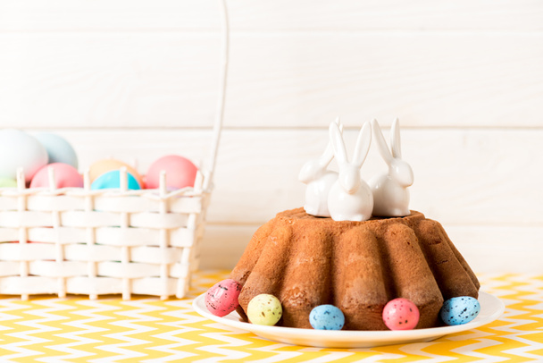 Gâteau de Pâques avec lapins en céramique et œufs de caille peints sur la table
  - Photo, image