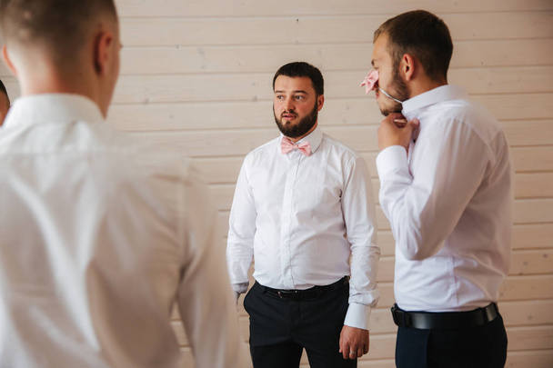 Man prepares for wedding at home. Groom with friends dressed at home, good mood - Photo, Image