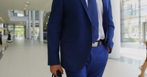 Low angle view of a Caucasian businessman holding his briefcase and walking in the office lobby  - Metraje, vídeo