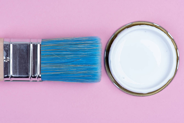 Can tin of white paint and paintbrush on pastel pink background top view - Foto, immagini