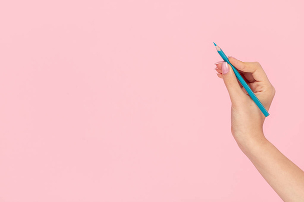 Девушка с урожая рисует голубым карандашом на розовом фоне
  - Фото, изображение