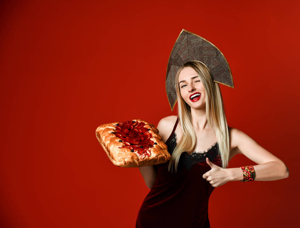 Portrait of a young beautiful blonde holding a delicious homemade cherry pie. - Фото, изображение