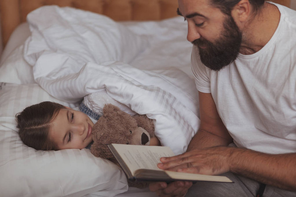 Mature bearded man resting at home with his little daughter - Фото, зображення