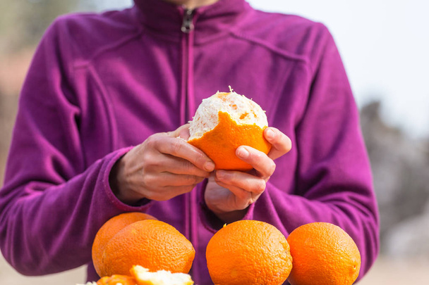 Frau schält Orangen von der Schale.  - Foto, Bild