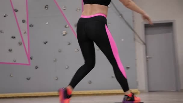 low angle shot smiling lady in black and pink leggings does step aerobics on platform close view slow motion - Záběry, video
