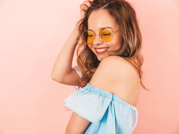 Portrait of beautiful smiling cute model in round sunglasses. Girl in summer hipster colorful clothes. Model posing on pink  background - Foto, immagini