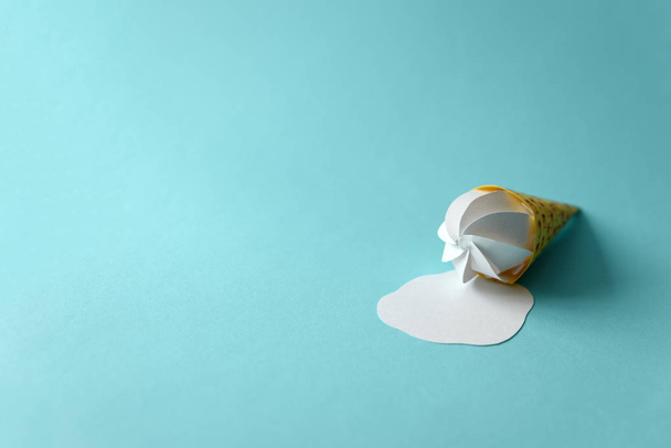 Cône de glace à la vanille en papier fondu sur fond bleu. Espace de copie. Concept alimentaire créatif ou artistique
 - Photo, image