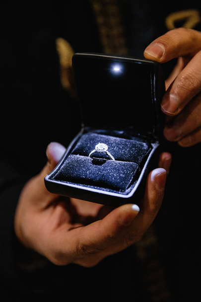 Echte leven voorstel: Man houdt een verlichte verlovingsring - blauwe bruid ring met een grote juweeltje - Foto, afbeelding