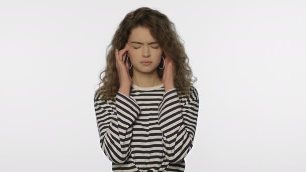 Müde Frau Kopfschmerzen auf weißem Hintergrund. Porträt einer aufgebrachten Frau, die den Kopf berührt - Filmmaterial, Video