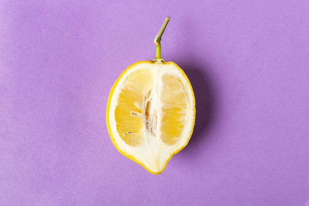 Half of ripe lemon on purple background, top view, minimal compo - 写真・画像