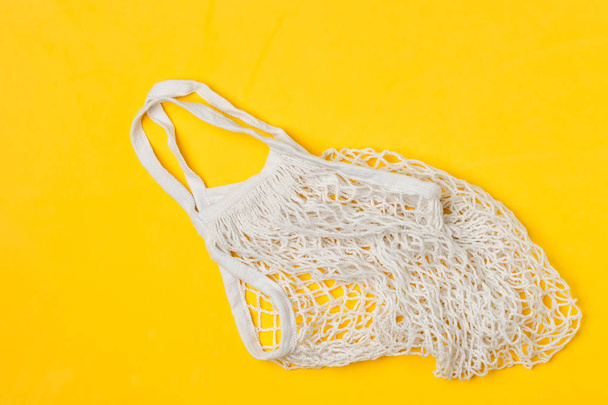 White cotton mesh reusable shopping bag, yellow background, top  - Fotoğraf, Görsel