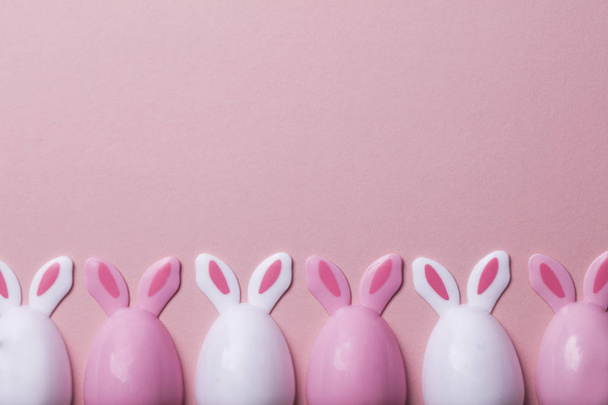 Easter eggs with bunny ears on a pastel pink background - Zdjęcie, obraz