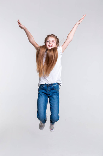 Playful happy blonde girl highly jumping with pulled hands - Фото, изображение