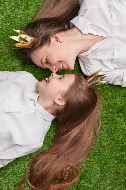 Mother and daughter touching noses on grass - 写真・画像