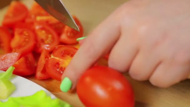 La mujer corta con un cuchillo un tomate cereza sobre una tabla de madera. El tiempo pasa. Primer plano
 - Metraje, vídeo