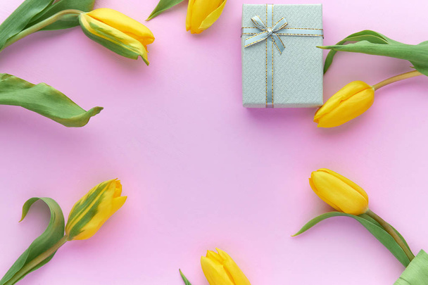 Tulipanes amarillos y cajas de regalo sobre fondo rosa con espacio para copiar
 - Foto, imagen
