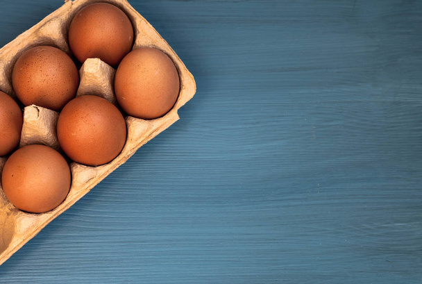 top view of eggs in a box on a blue wooden background. copy space - Foto, Bild