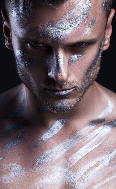 concept of creative portrait of a guy with a metal / silver carosis on the body. A strong look, a cry of strength and struggle with yourself - Photo, Image