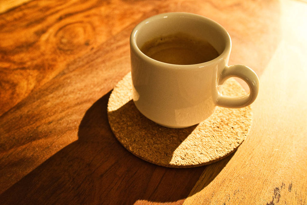 Una taza de espresso en un plato de madera bajo la luz del sol. Lugar para el texto
 - Foto, Imagen