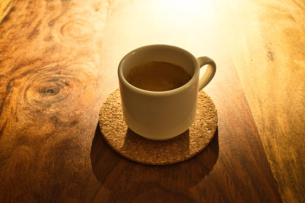 Kuppi espressoa puulevyllä hämärässä auringonvalossa. Tekstipaikka
 - Valokuva, kuva