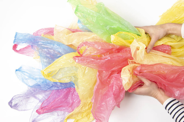 Woman hands holding many plastic bags over white background. No plastic, environmental, pollution concept - Fotografie, Obrázek