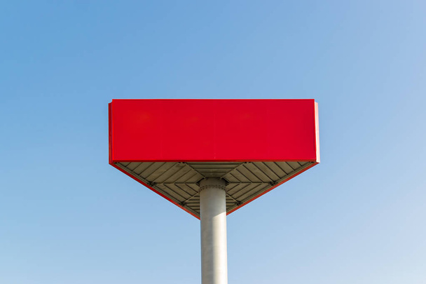 Empty red billboard with copy space on the background of a blue sky. Red mockup with place for your text. Large banner mockup for advertisements. - 写真・画像