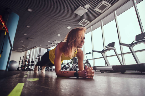 Femme mince fitness travaillant dans la salle de gym moderne, faire la planche sur un tapis
 - Photo, image