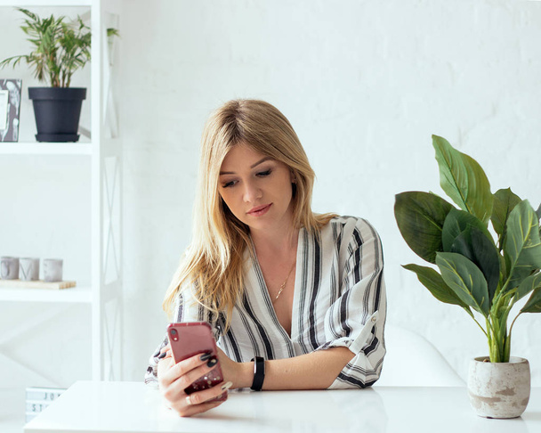 Neşeli genç güzel redhaired kadın gözlük Cafe kahve ile üzerinde çalışma evinde otururken ona telefon, dokunmatik yüzey ve dizüstü bilgisayar kullanarak. - Fotoğraf, Görsel