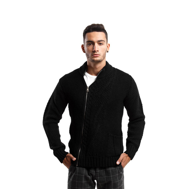 Young man dressed in black sweater with a zipper and gray plaid pants stands on the white background - Photo, image