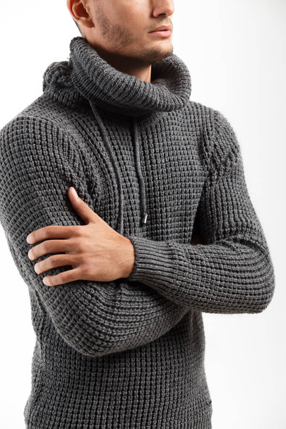 Young man dressed in gray sweater stands on the white background - Foto, Bild
