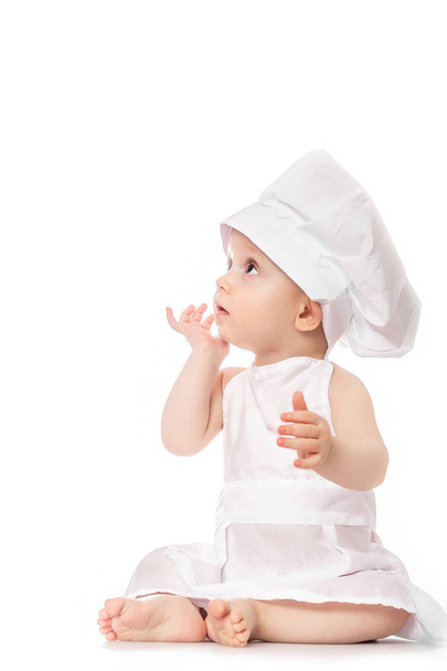 ten months old baby in a suit of the cook surprised and smiling in the kitchen. Small kid as a little cook or scullion make pizza in chef suit. Cooking child lifestyle concept. Toddler playing - Photo, Image