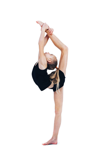 A little girl in a gymnastic costume raises her leg - Φωτογραφία, εικόνα