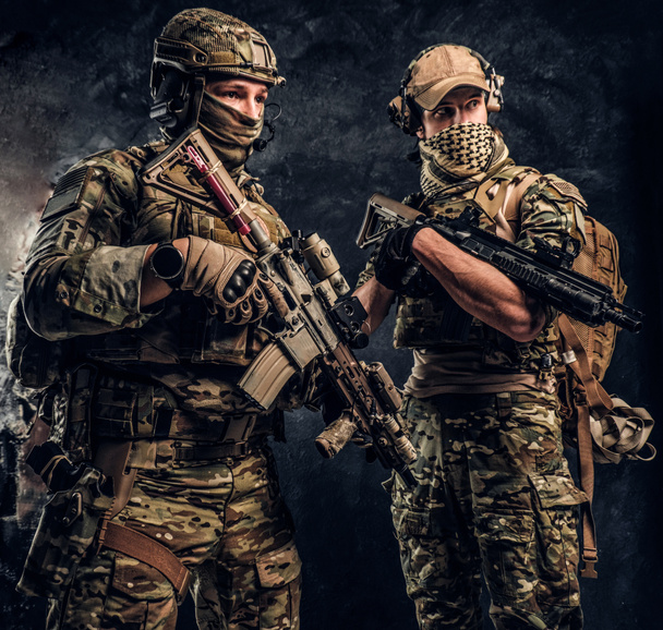 Twee soldaten van de speciale troepen in volledige beschermende uitrusting met geweren. Studio foto tegen een donkere muur. - Foto, afbeelding