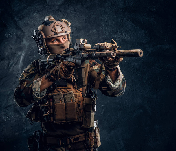 Элитный отряд, солдат спецназа в камуфляжной форме держит штурмовую винтовку с лазерным прицелом и целится в цель
. - Фото, изображение