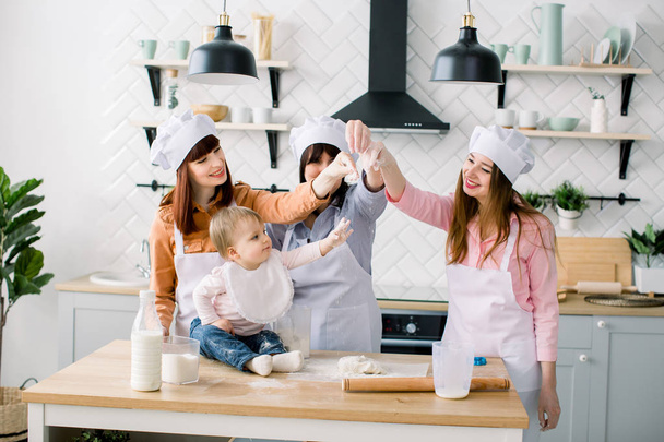 Three generations of women in white aprons are making pizza dough in the kitchen to Mothers Day - 写真・画像