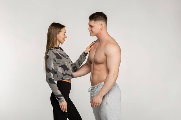 Kaunis urheilullinen pari, urheilullinen tyttö ja lihaksikas paidaton mies
 - Valokuva, kuva