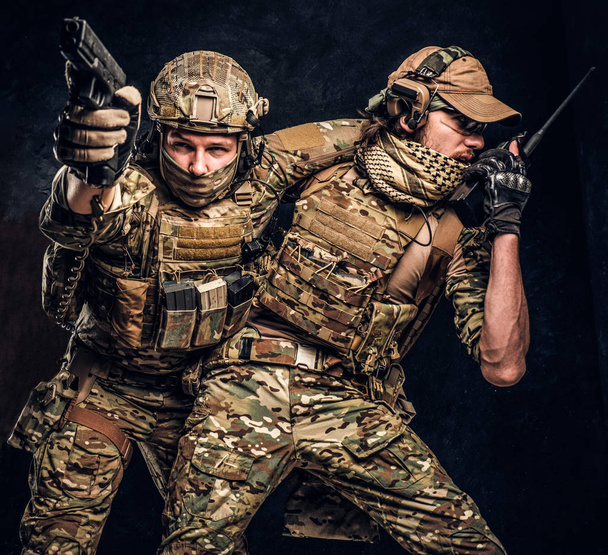 Combat conflict, special mission. The military soldier carrying teammate out of the battlefield. Studio photo against a dark wall - Photo, Image