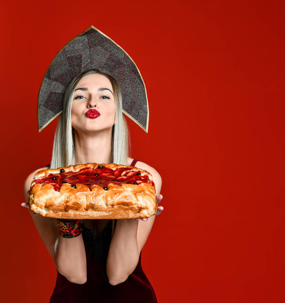 Portrait of a young beautiful blonde in headscarf holding a delicious homemade cherry pie. - Foto, afbeelding