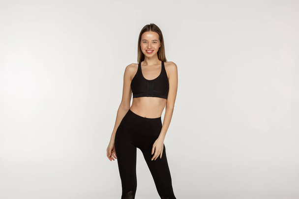 Menina magra nova em um terno apertado preto para ioga e fitness
 - Foto, Imagem