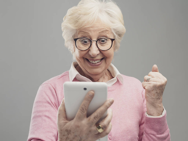Happy surprised senior lady using a digital tablet - Foto, Bild