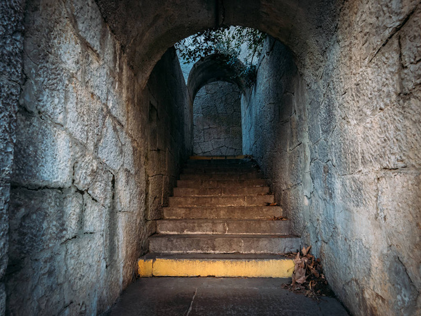 Old vintage steps of stone staircase in narrow corridor of ancient building - Photo, Image