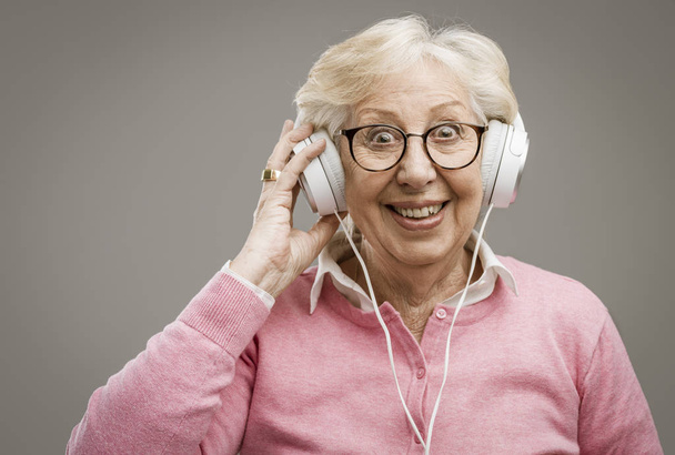 Happy senior woman wearing headphones - Valokuva, kuva