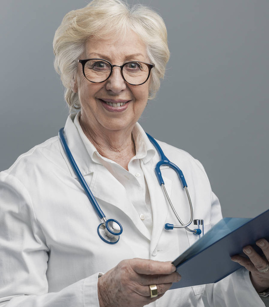 Confident senior female doctor posing and smiling - Foto, Imagem