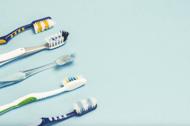 Several different used toothbrushes on a blue background. Toothbrush change concept, oral hygiene, big and friendly family, toothbrush selection. - Photo, Image