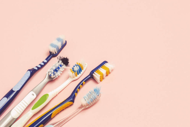 Useita erilaisia käytettyjä hammasharjoja vaaleanpunaisella taustalla. Hammasharja muutos käsite, suuhygienia, iso ja ystävällinen perhe, hammasharja valinta. Tasainen, ylhäältä
. - Valokuva, kuva