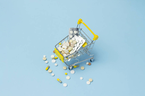 Shopping cart from the supermarket full of pills on a blue background. Purchases of medical preparations, purchase on the Internet. Flat lay, top view. - Φωτογραφία, εικόνα