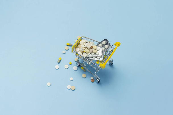 Shopping cart from the supermarket full of pills on a blue background. Purchases of medical preparations, purchase on the Internet. Flat lay, top view. - Fotoğraf, Görsel